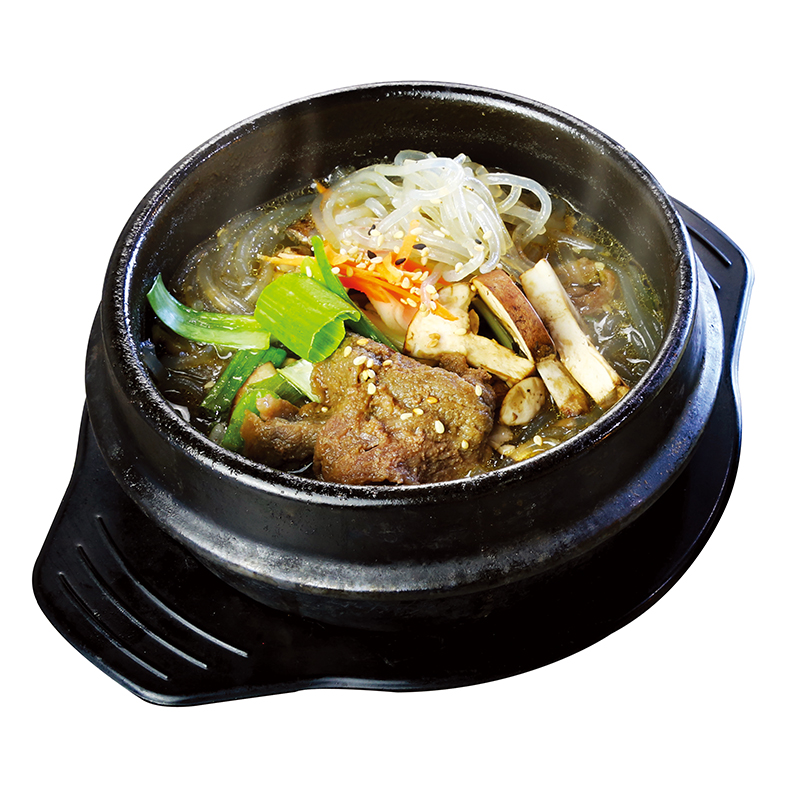 Hot beef bone stew with glass noodles, mushrooms and green onion in black stone pot at K-Bop, a Korean Restaurant in Austin