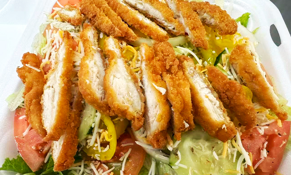 A garden salad topped with crispy fried chicken strips at Kick Off Wings, a Fast Food Restaurant in Carrollton