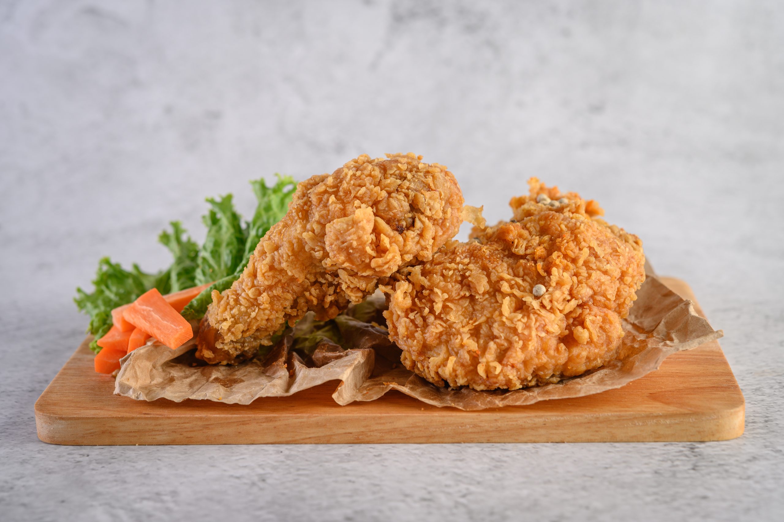 Crispy fried chicken on a wooden cutting board.