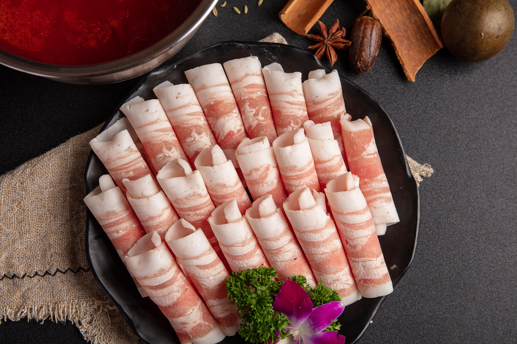 Neatly arranged lamb rolls on a black plate at King Pot Korean BBQ & Hot Pot, a Asian Fusion restaurant in Greeley