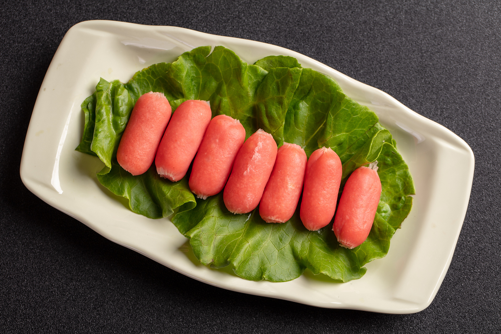 Small sausages on lettuce in a white plate at King Pot Korean BBQ & Hot Pot, a Asian Fusion restaurant in Greeley