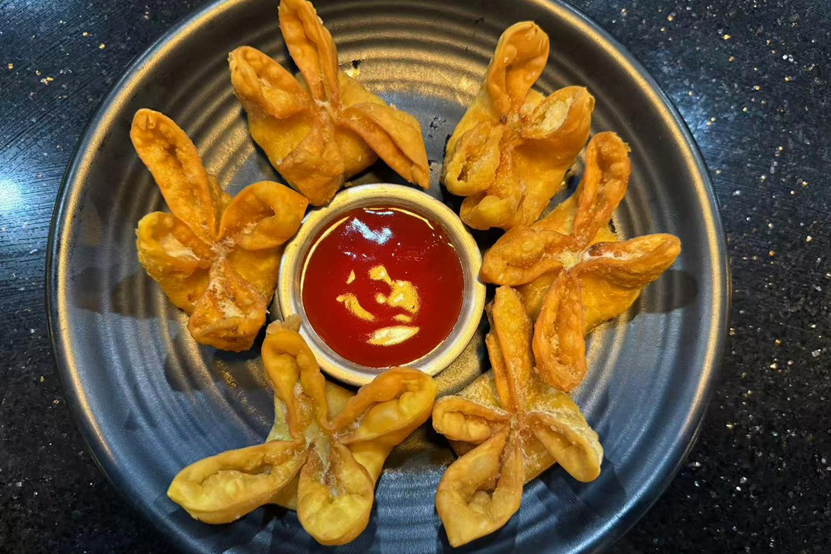 Six golden fried wontons with sweet chili dipping sauce on dark plate at Kings Sushi, a Japanese Restaurant in Summerville