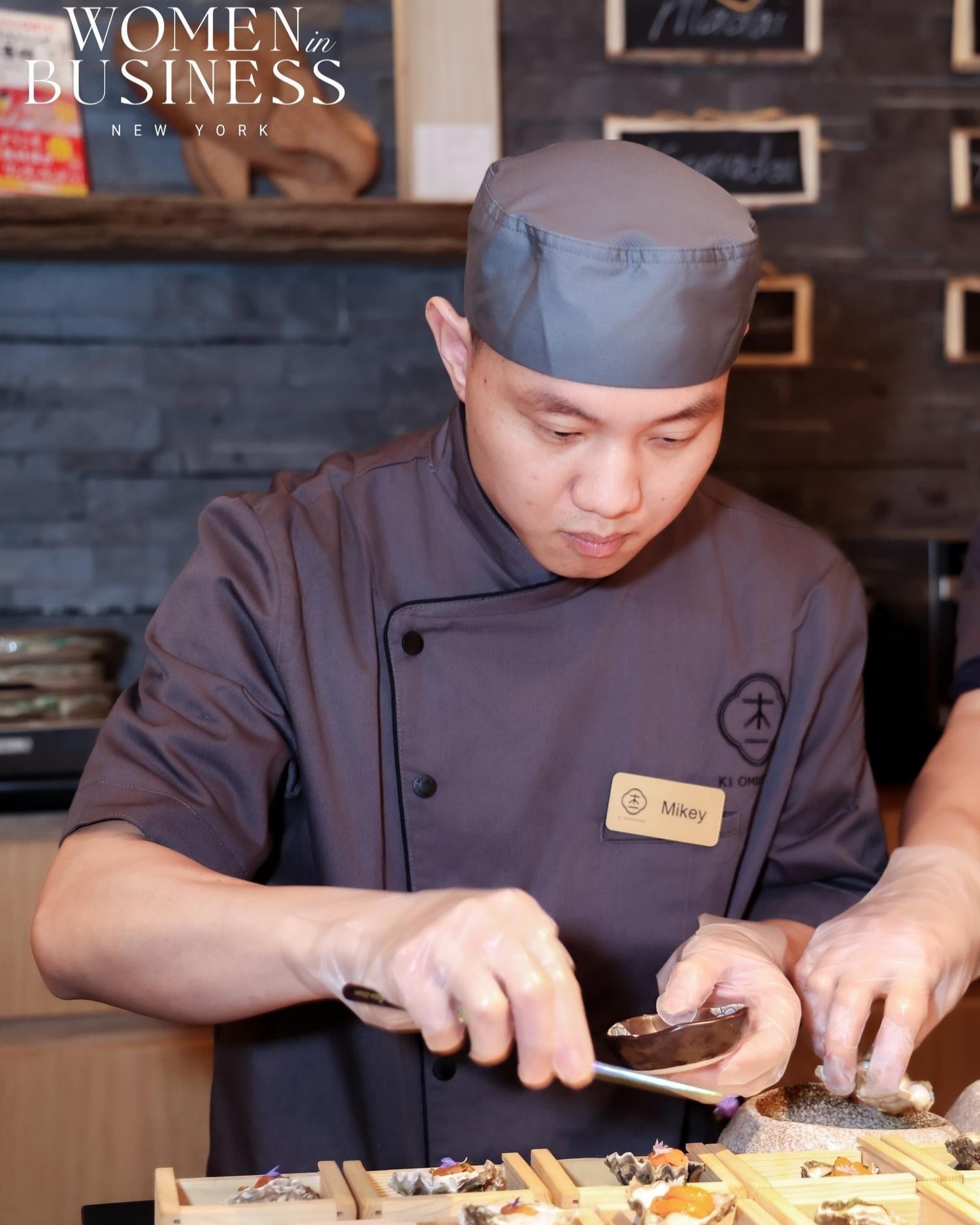 Chef Mikey assembles seafood starters at wooden bar at Ki Omakase, a Sushi Restaurant in Little Neck