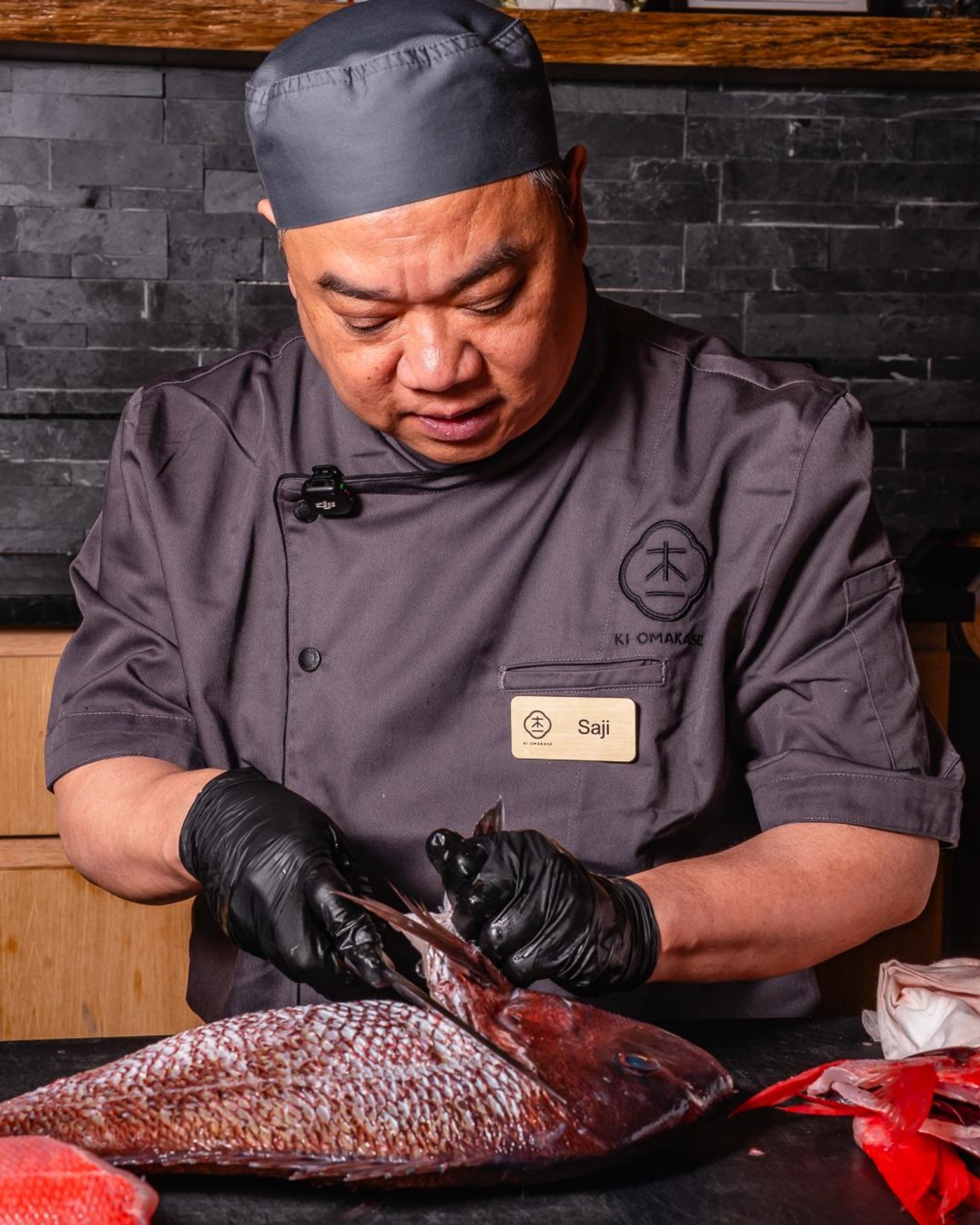 Chef Saji cleans whole red fish at prep station at Ki Omakase, a Sushi Restaurant in Little Neck