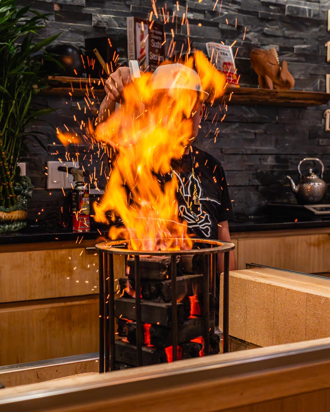 Chef cooks food over blazing charcoal grill at Ki Omakase, a Sushi Restaurant in Little Neck
