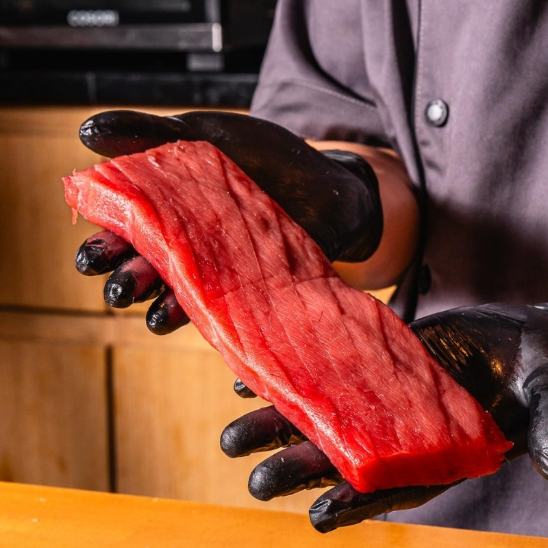 Chef holds glossy raw tuna fillet at Ki Omakase, a Sushi Restaurant in Little Neck