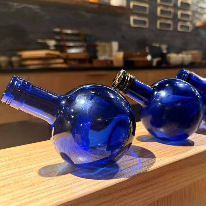 Empty cobalt blue glass bottles arranged on bar counter at Ki Omakase, a Sushi Restaurant in Little Neck