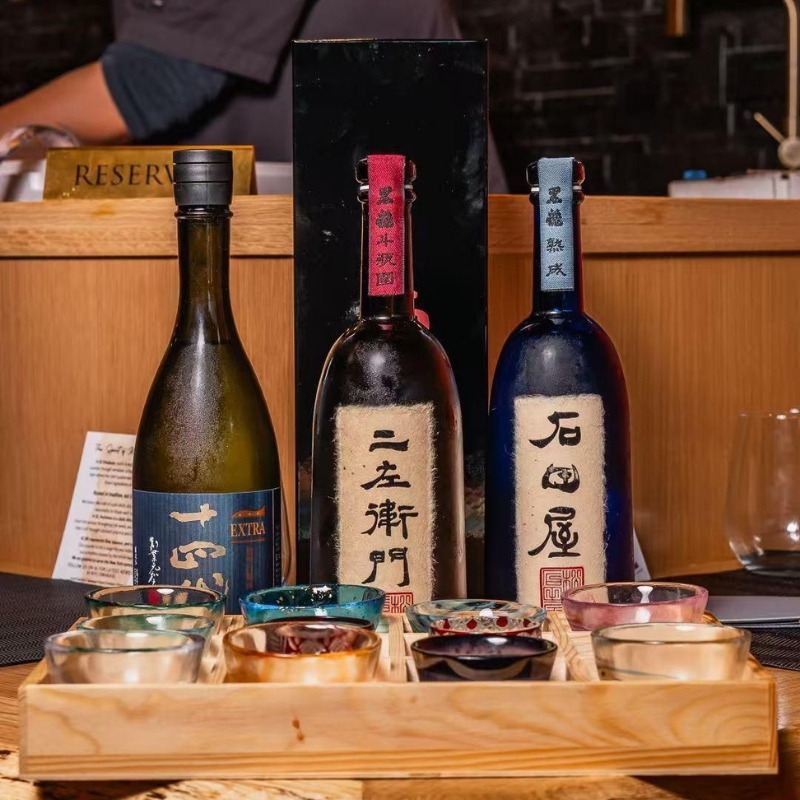 Selection of fine sake bottles with tasting glass set at Ki Omakase, a Sushi Restaurant in Little Neck