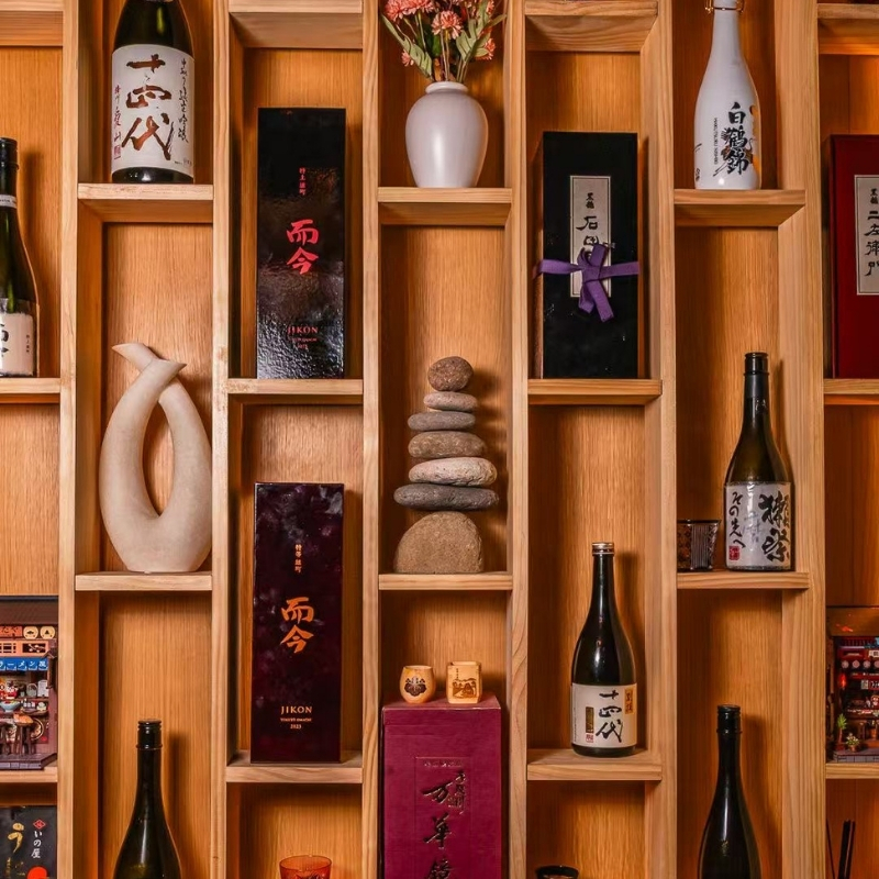 Wooden shelving stocked with premium sake bottles at Ki Omakase, a Sushi Restaurant in Little Neck