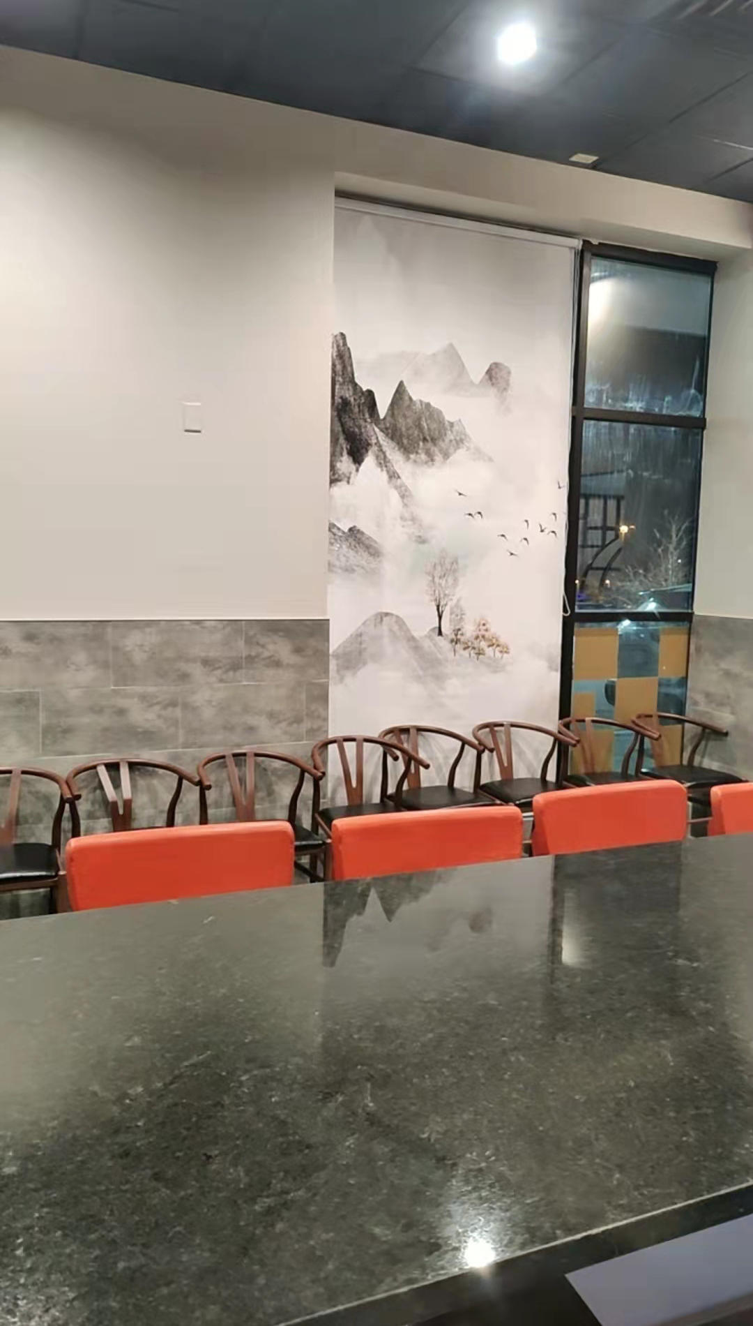 Long dark dining table with orange chairs at Kirin Hot Pot, a Chinese Restaurant in Broomfield