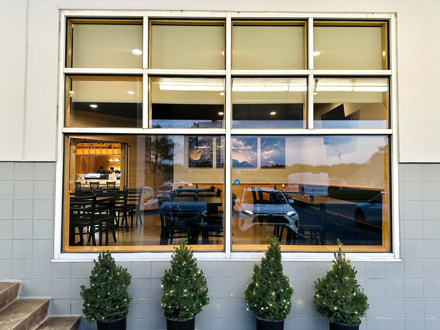 Exterior window showing interior seating and decorated with small trees at Kiwami Ramen & Sushi, a Japanese Restaurant in Overland Park