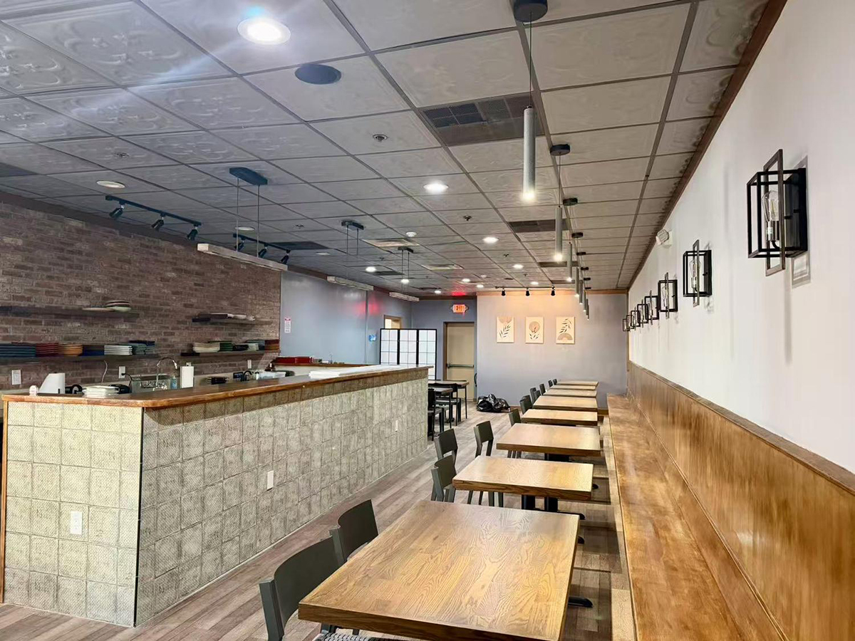 Interior of Kojo Restaurant showing long dining tables, bench seating, and the kitchen counter with shelves