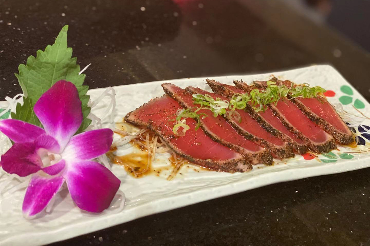 Seared pepper crusted tuna sashimi garnished with orchid and green onion at Komeya Sushi & Ramen, a Japanese Restaurant in Spring