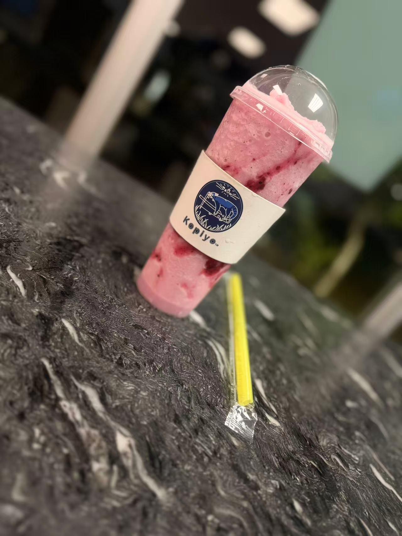 Pink berry slush drink in a Kopiyo cup with a yellow straw at Kopiyo, a Coffee shop in Flowood