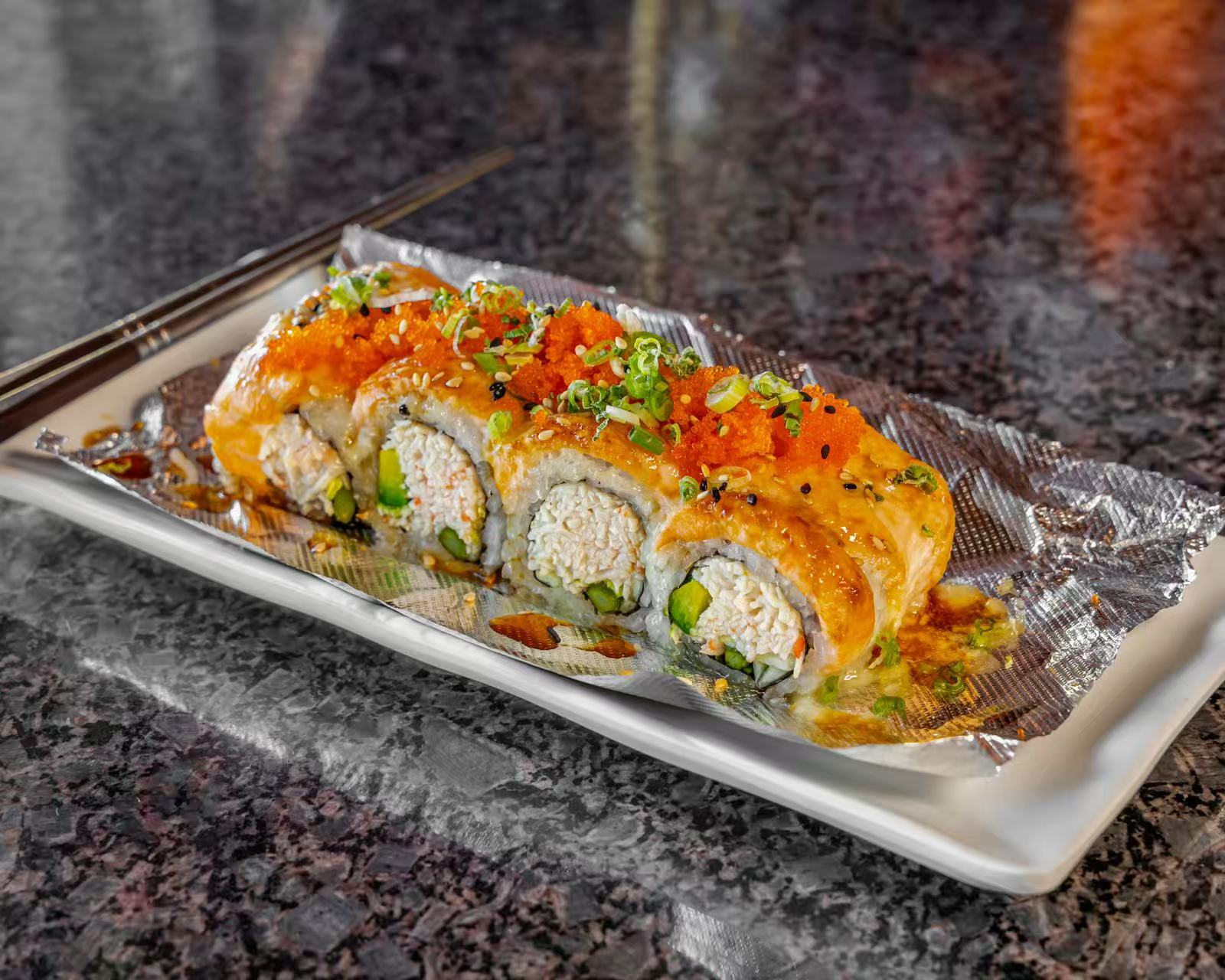A sushi roll with crab, avocado, topped with eel and fish roe, served on foil at Koya Sushi, a Sushi Restaurant in Norco