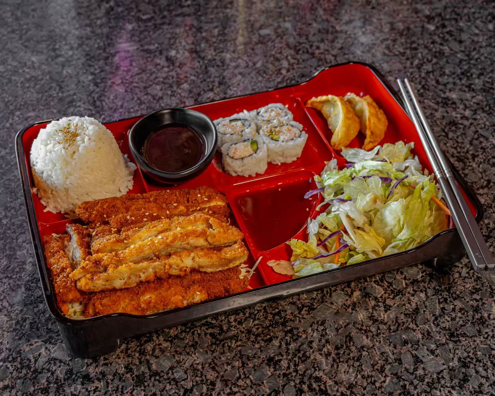 A bento box with chicken katsu, rice, sushi, dumplings, and salad at Koya Sushi, a Sushi Restaurant in Norco