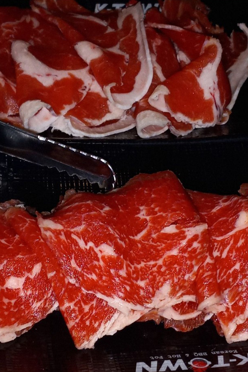 On the plate are bright red raw beef slices with clear texture at K-Town Korean BBQ & Hotpot, a Korean BBQ & Hotpot Restaurant in Fort Wayne