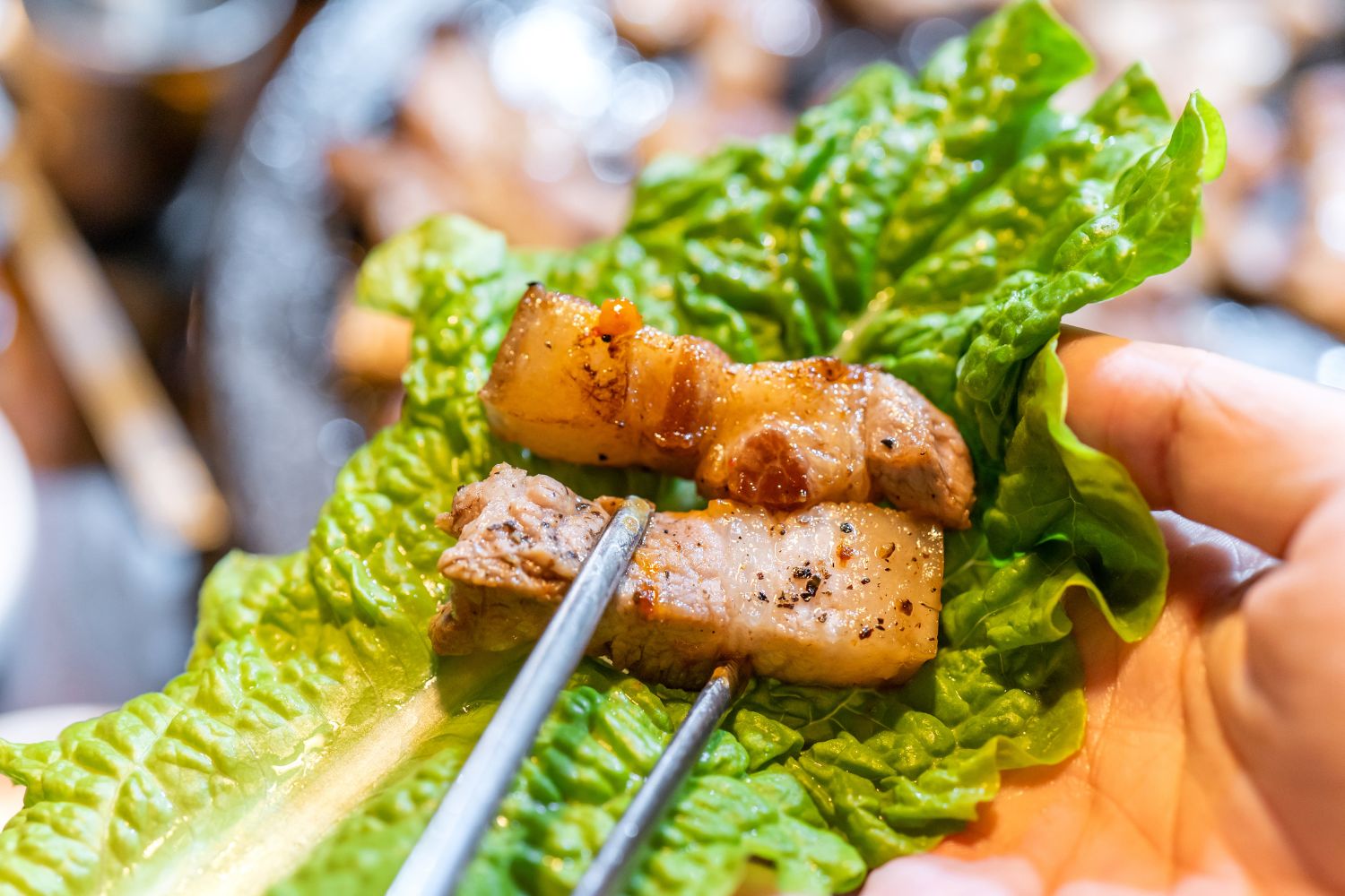 Grilled pork belly pieces wrapped in fresh lettuce at K-town Korean BBQ Restaurant in Hemet
