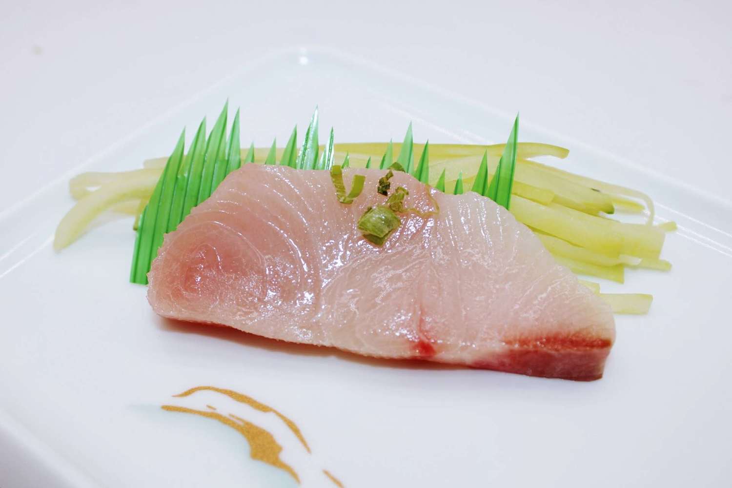 Single slice of raw fish sashimi garnished with scallions at Kumamon Sushi & Ramen AYCE, a Japanese Restaurant in Wilmington