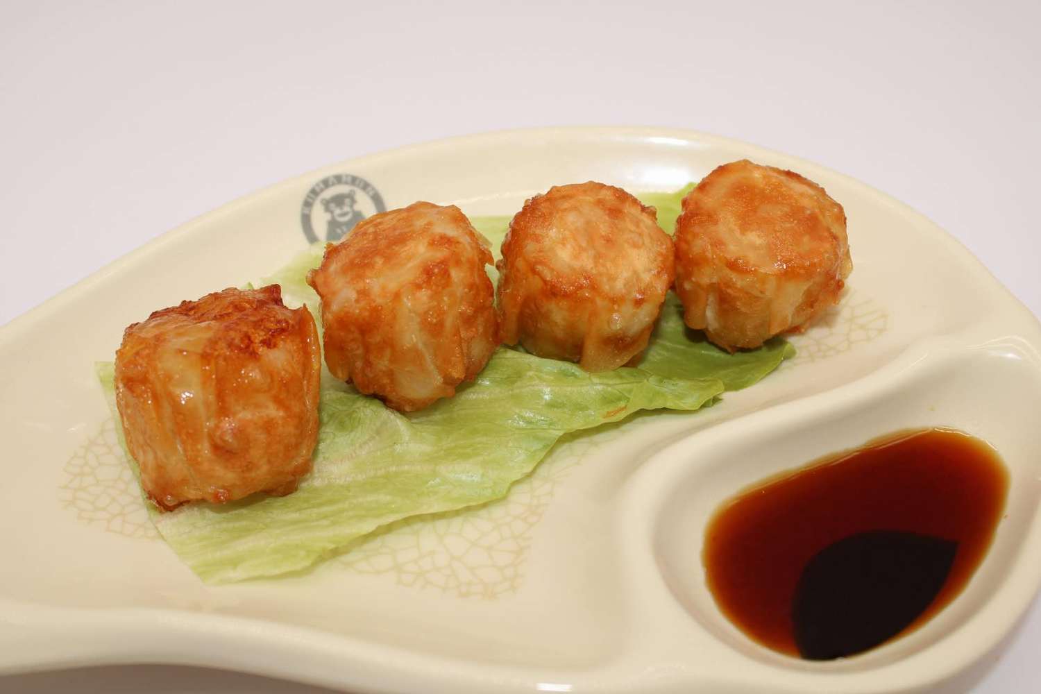 Four fried shumai with sauce on a plate at Kumamon Sushi & Ramen AYCE, a Japanese Restaurant in Wilmington