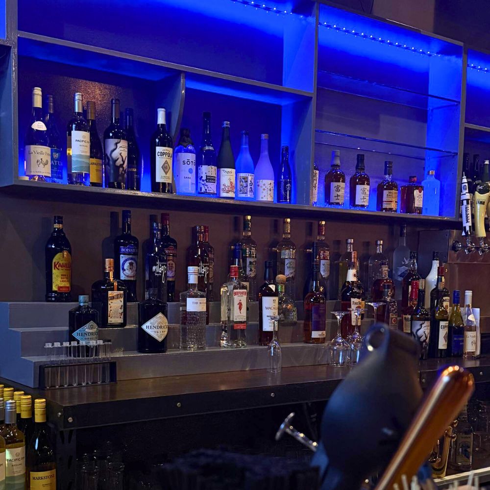 Blue-lit liquor shelf with various spirits at Kumo, a Japanese Restaurant in Schererville