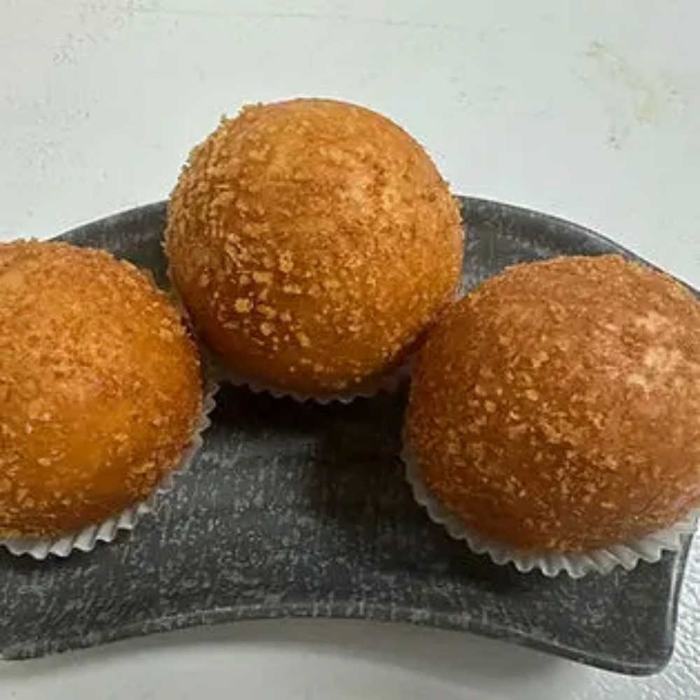 Three crispy fried golden balls on dark plate