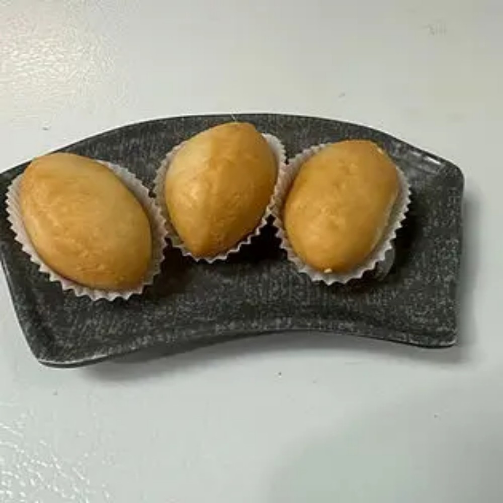 Three golden fried buns on dark plate