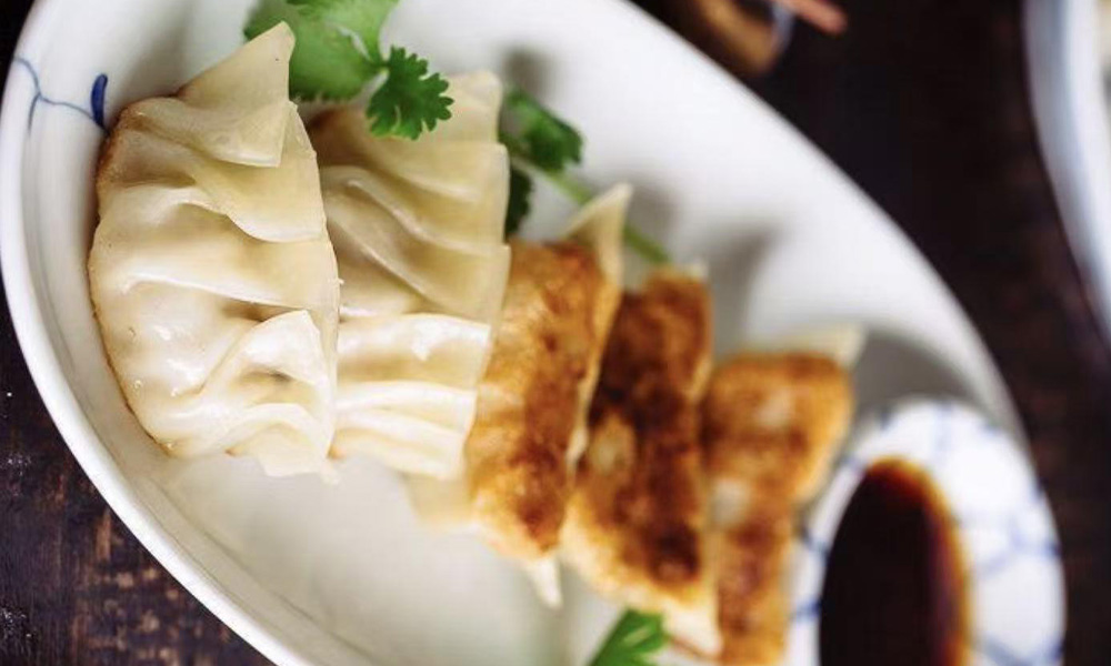 Pan-fried potstickers with cilantro and soy dipping sauce on a plate at Kung Fu Noodle House, a Chinese restaurant in West Allis