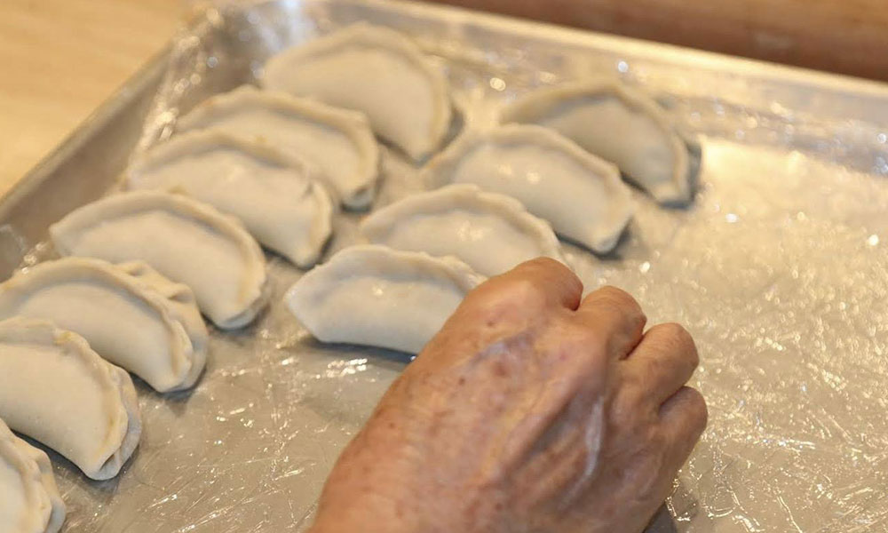 Hand-folded uncooked dumplings resting on a foil-lined baking tray at Kungfu Noodles & Dumplings, a Chinese restaurant in College Station