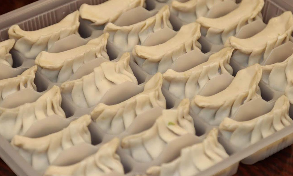 Frozen uncooked dumplings neatly arranged in a plastic tray for storage at Kungfu Noodles & Dumplings, a Chinese restaurant in College Station