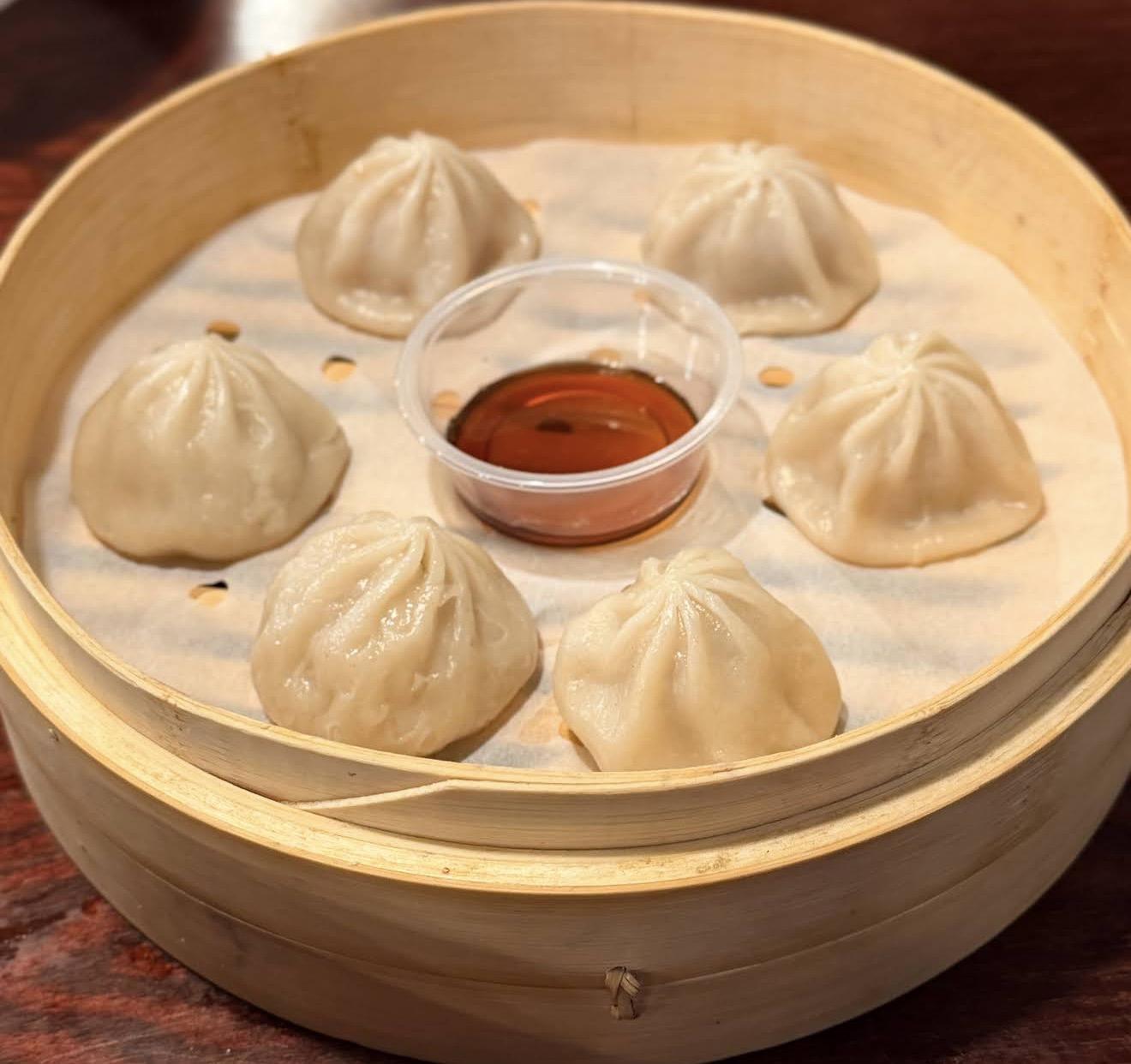Steamed pork soup dumplings (xiaolongbao) in a bamboo steamer with soy sauce at Kungfu Noodles & Dumplings, a Chinese restaurant in College Station