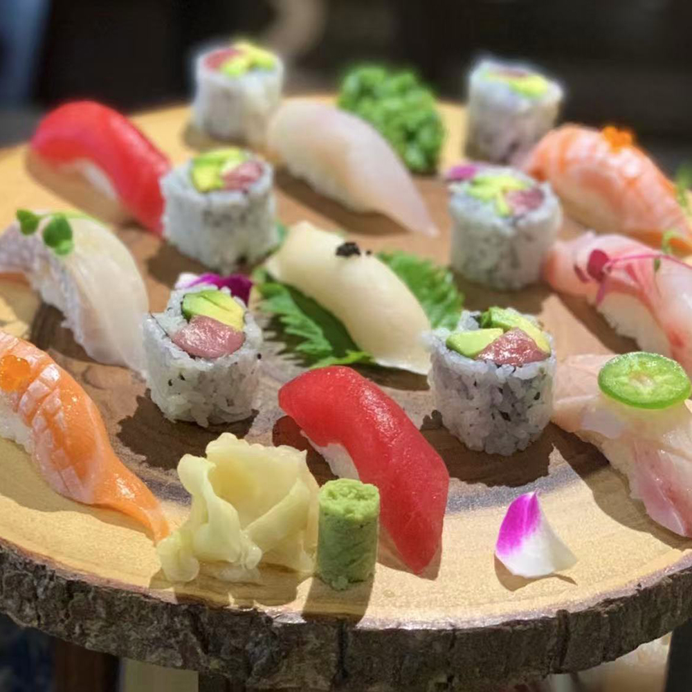 Lava-Buffet & Sushi-Asian-Fusion-Restaurant-assorted-sushi-Kilgore A small platter of assorted sushi, including various nigiri and maki rolls, garnished with wasabi, pickled ginger, and a flower petal, arranged on a wooden plate at Lava Buffet & Sushi,a Asian Fusion Restaurant in Kilgore