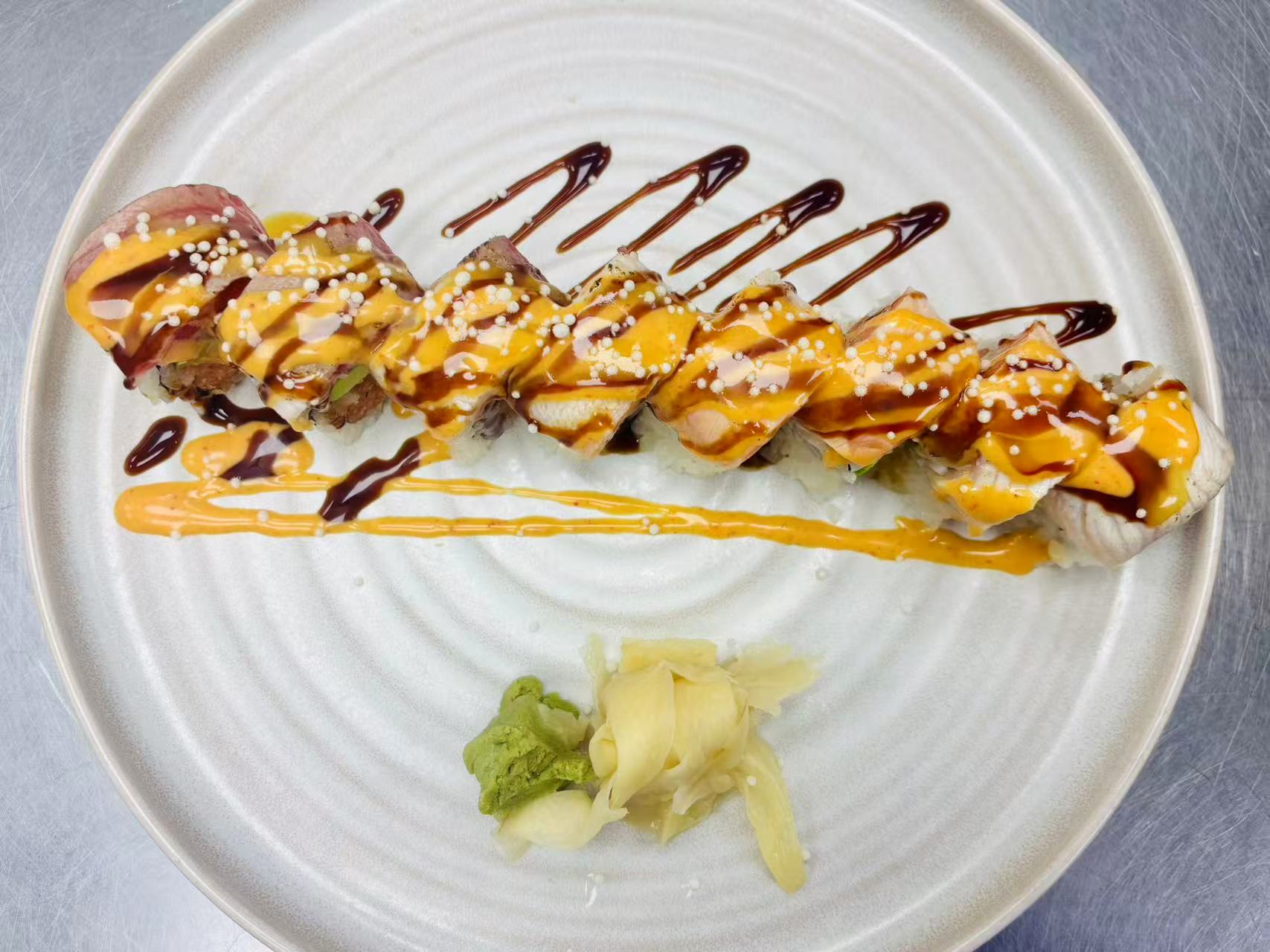 Lava-Buffet & Sushi-Asian-Fusion-Restaurant-Sauced-Fish-Sushi-Roll-Kilgore Sushi roll with fish, dual sauces and sesame pearls at Lava Buffet & Sushi,a Asian Fusion Restaurant in Kilgore