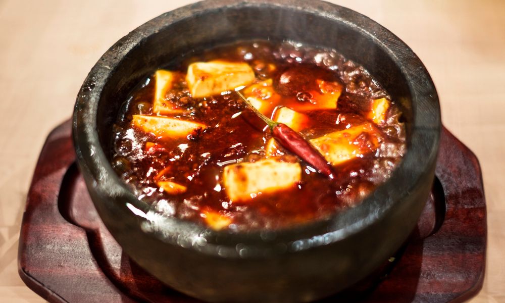 Spicy mapo tofu simmering in a stone pot with red chili oil at Legend Asian Fusion, a Asian fusion restaurant in Colonia