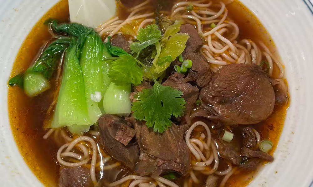 Spicy beef noodles with greens in savory broth at Licious Noodles & Bao, a Chinese Dumpling Restaurant in Rockledge
