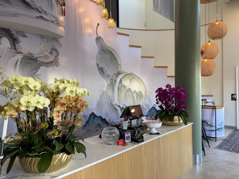 Reception desk with orchids and artistic mural at Linglong, a Chinese Restaurant in Fountain Valley.