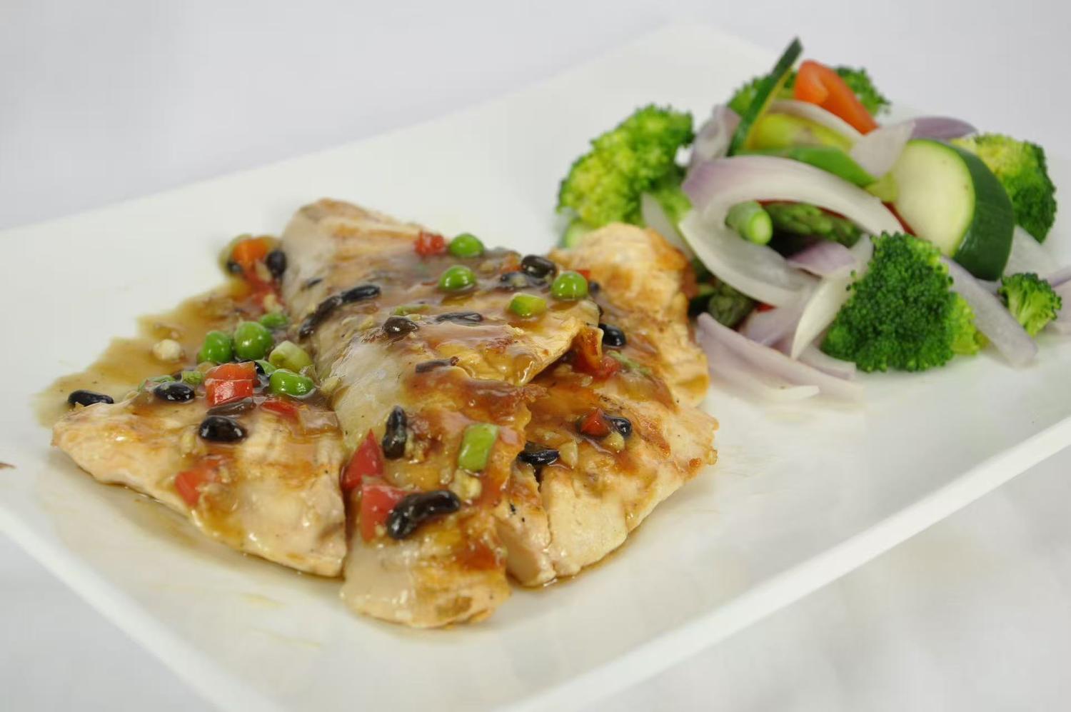 Grilled salmon fillet topped with black beans and green peas.