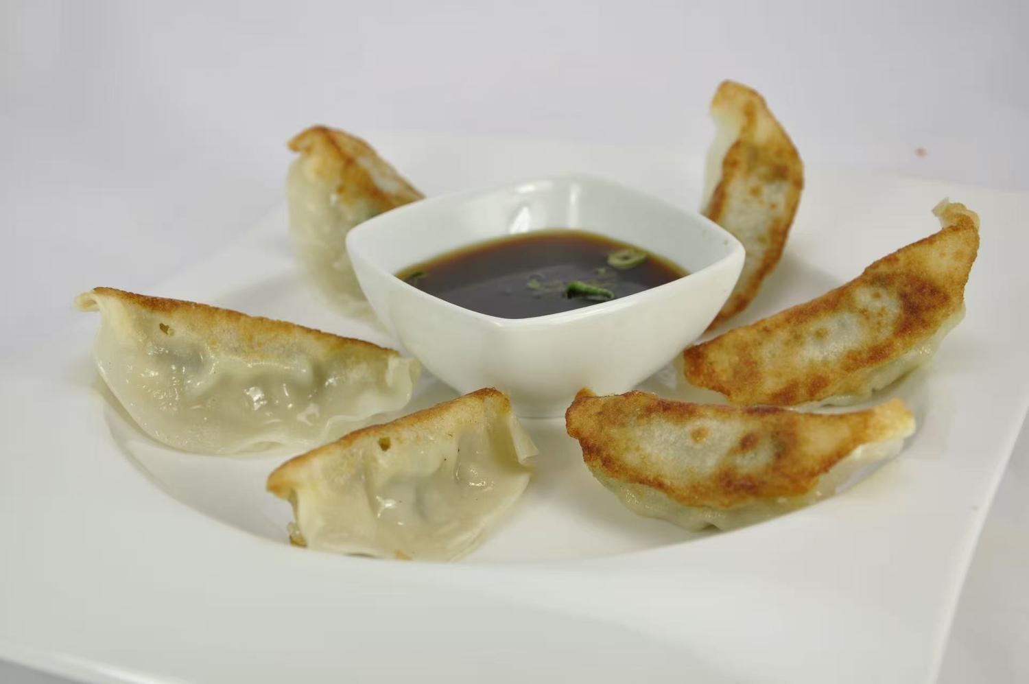 Crispy pan - fried dumplings with dipping sauce.