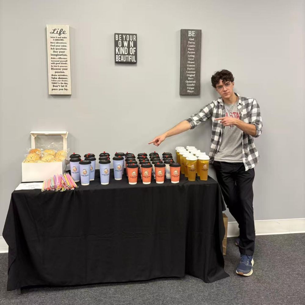 A young man points at assorted LuCha drink cups on display at LuCha Bubble Tea & Cafe, Bubble Tea Store in OH A young man points at assorted LuCha drink cups on display at LuCha Bubble Tea & Cafe, Bubble Tea Store in OH