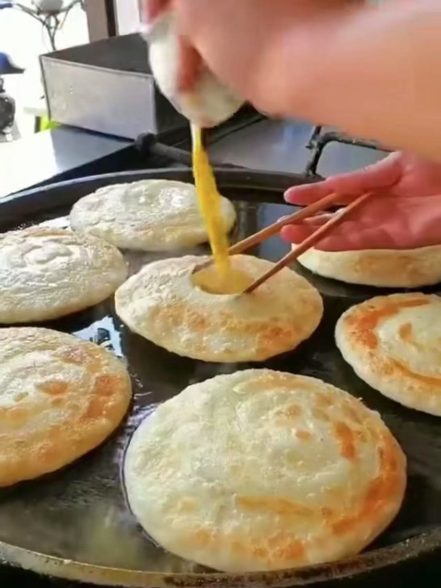 Making egg - stuffed pancakes, pouring egg into the pancake at Tao's Bao，a Chinese Restaurant in Stony Brook