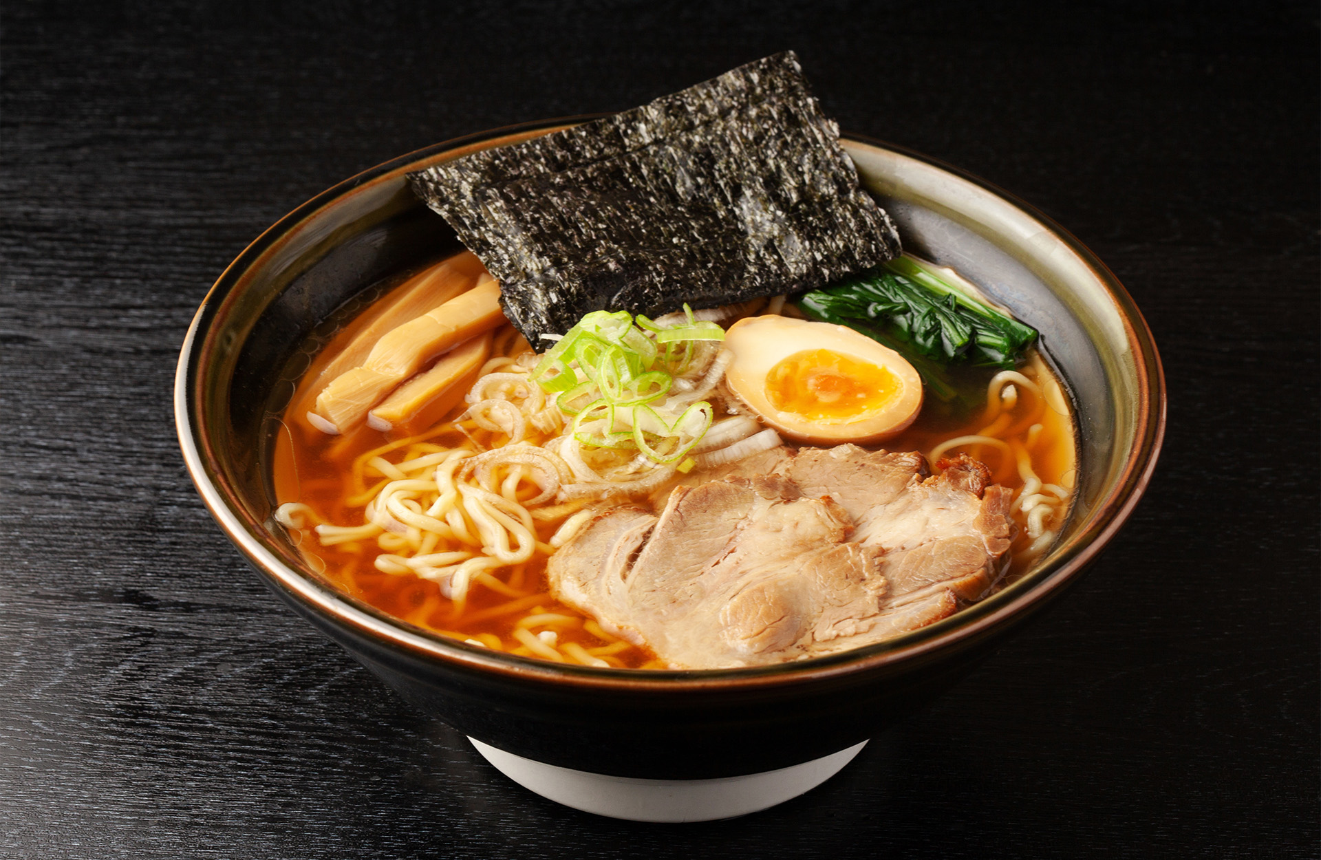 Ramen bowl with noodles, chashu pork, soft-boiled egg, nori, and scallions