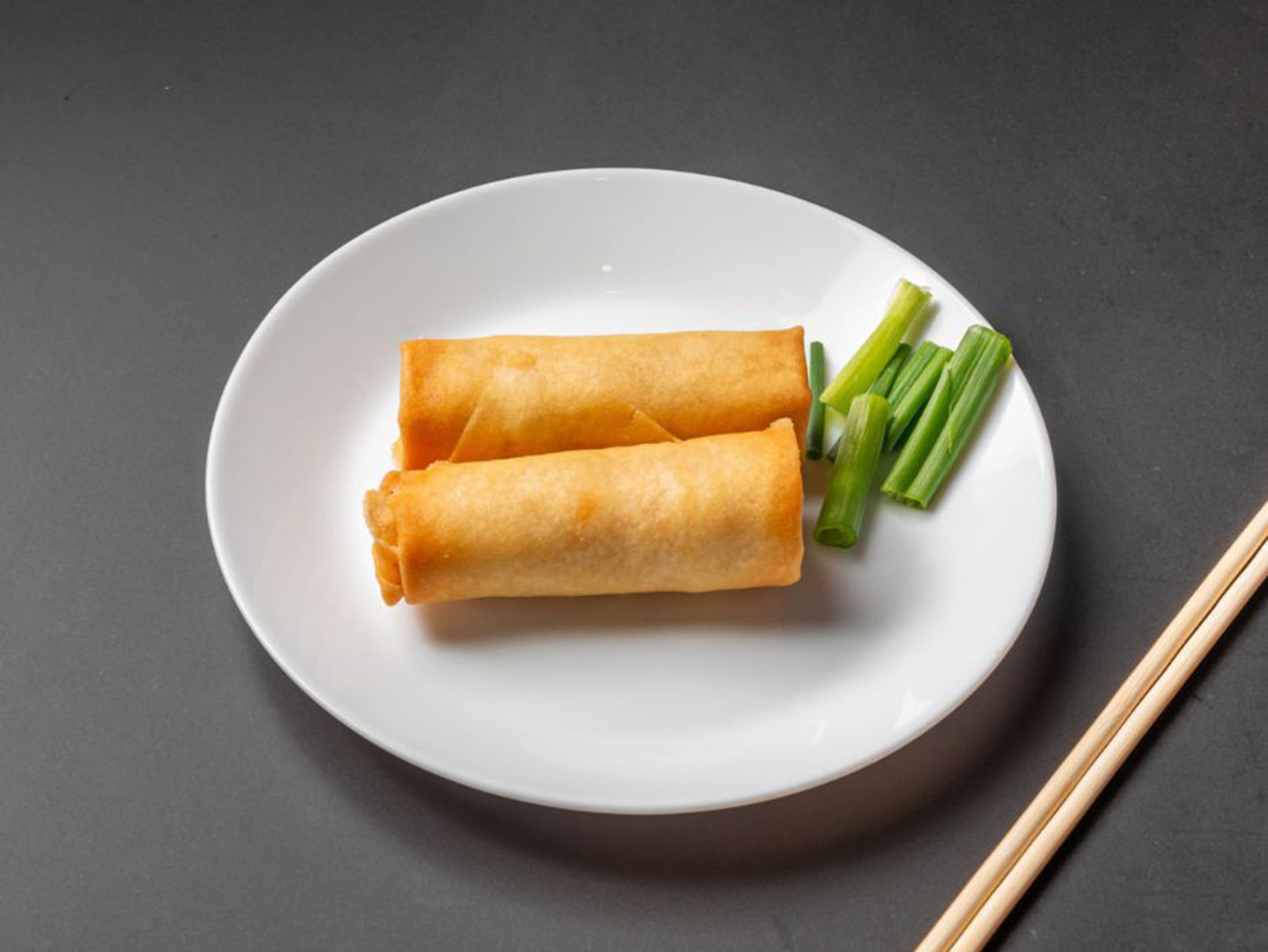 Two crispy fried vegetable spring rolls with green onion garnish at Lucky Dragon, a Chinese Restaurant in New York