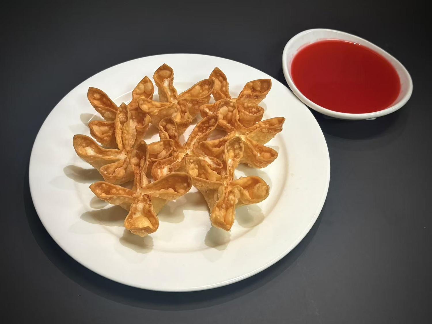 Crispy fried cheese wontons on white plate with red sweet‑sour dipping sauce at Lucky House, a Chinese restaurant in Surprise