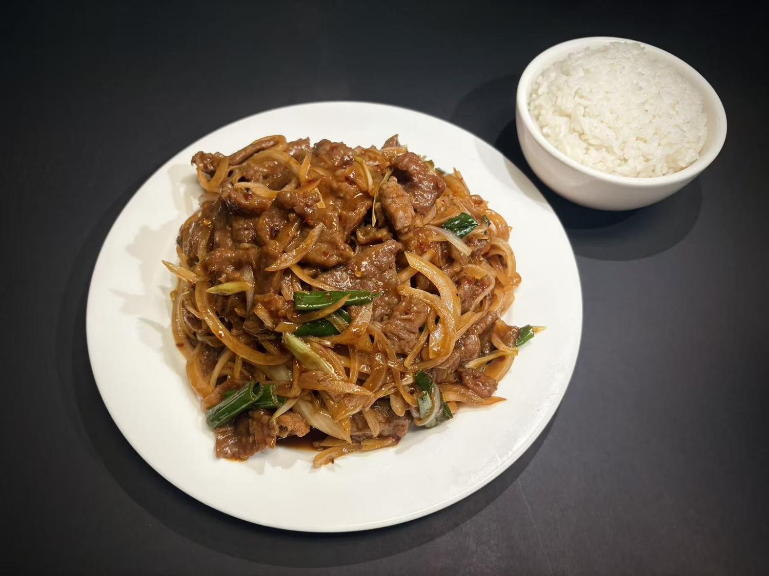 Stir‑fried beef with onions and green scallions, served with steamed white rice at Lucky House, a Chinese restaurant in Surprise