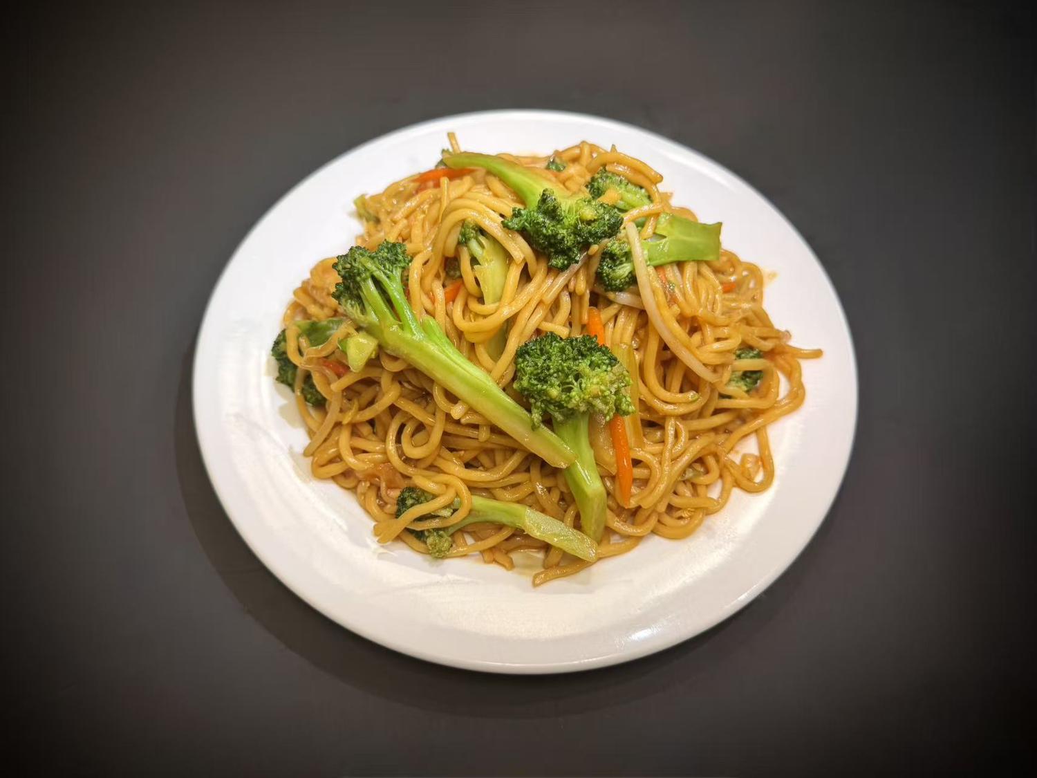 Vegetable lo mein noodles topped with fresh broccoli and carrot strips on white plate at Lucky House, a Chinese restaurant in Surprise