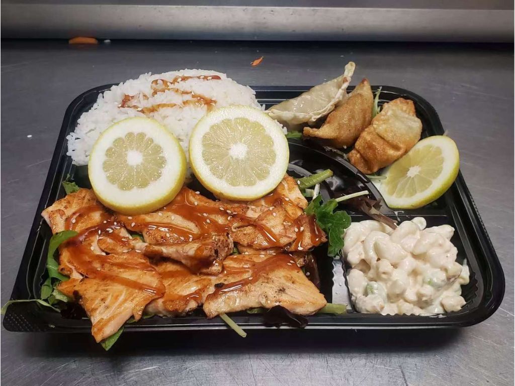 Bento box with grilled salmon, white rice, potstickers, macaroni salad, and lemon slices at Luv Ramen & BBQ, a Japanese restaurant in Hawthorne