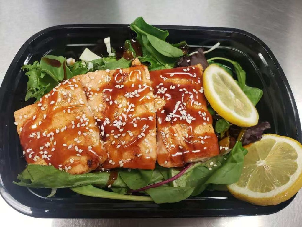 Salad bowl with grilled salmon topped with sesame seeds, mixed greens, and lemon slices at Luv Ramen & BBQ, a Japanese restaurant in Hawthorne