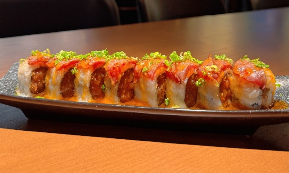 Bacon-topped sushi roll with crispy fried filling and spicy sauce at Machi Sushi, an Asian Restaurant in Houston