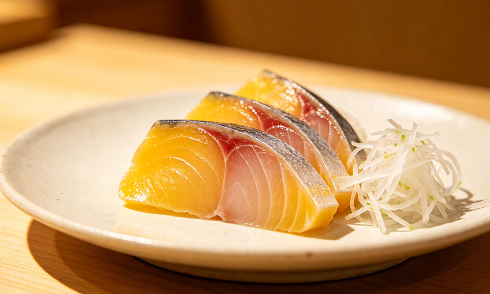 Three slices of yellowtail sashimi with shredded daikon radish