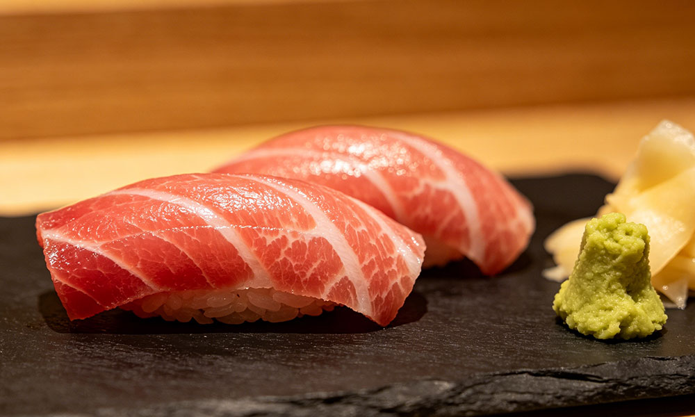 Two pieces of otoro tuna nigiri sushi with wasabi and pickled ginger